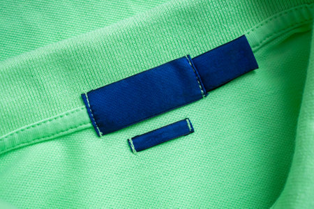 Blank blue laundry care clothes label on green shirt fabric texture background