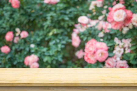 Empty wood table top with blur rose garden background for product displayの写真素材