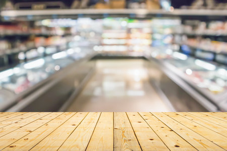 Empty wood table top with supermarket blurred background for product displayの写真素材