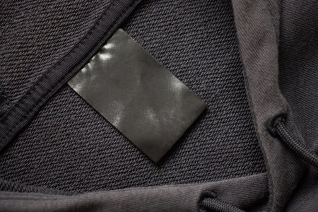 Blank black laundry care clothes label on black fabric texture backgroundの写真素材