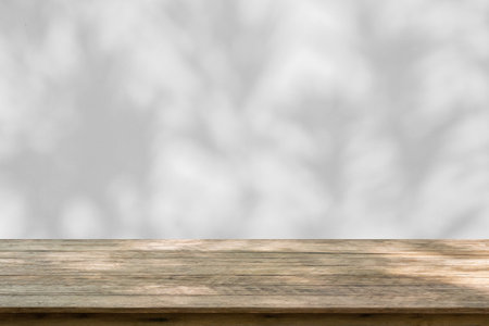 Empty wood table top on white wall texture with tree leaves shadow backgroundの写真素材