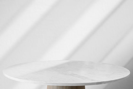 Round marble table top with abstract shadow drop on white wall background for mockup product displayの写真素材