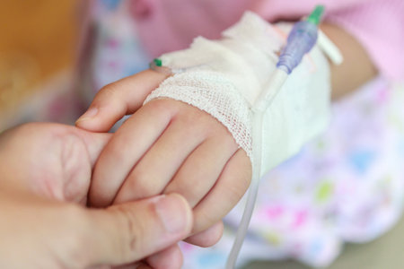Mother holding child hand with saline IV solution in hospitalの写真素材