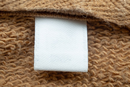 White blank laundry care clothes label on brown shirt fabric backgroundの写真素材
