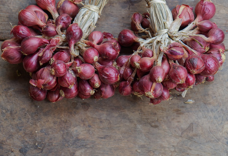 bunch of small red onions,Thai onions on wooden floorの写真素材