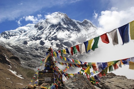 Annapurna South peak with a Buddhist stupa which is decorated with colorful prayer flags.