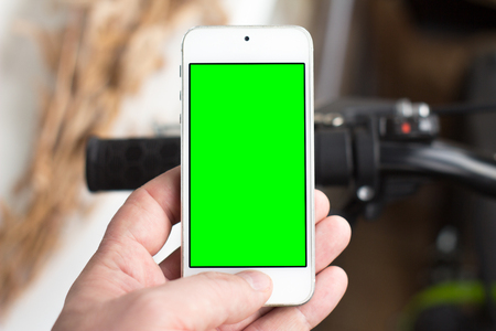 Man's hand use smartphone while he stands near by the road with bicycle. Green screenの写真素材