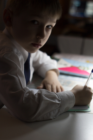 Boy hand with pencil writing english words by hand on traditional white notepad paper. Boy writes a letter to a friendの写真素材
