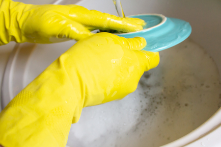Washing dishes in yellow gloves. Man handsの写真素材