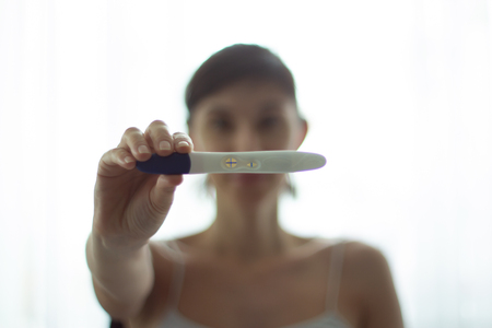Young woman with pregnancy test in hands. the test shows a positive resultの写真素材