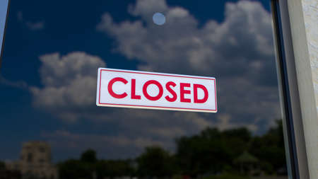 Closed Sign on Shop Window. Store sign. Close-up on a closed sign in the window of a shop displaying the message. The glass reflects the day city and the sky. 3d renderingの写真素材
