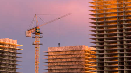 High building under construction. Side with cranes against blue sky with sun glare. 3d rendering