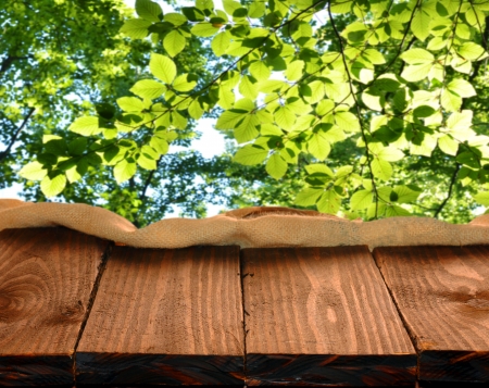 Empty wooden table and green forest leaves in backgroundの写真素材