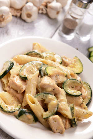 Penne pasta witch chicken and zucchini in cheese sauceの写真素材