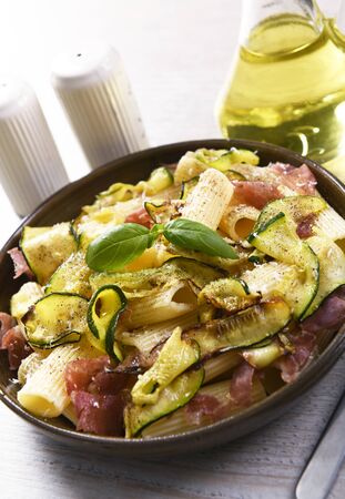 Tasty rigatoni pasta with courgette, prosciutto ham and grana padano cheeseの写真素材