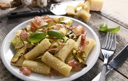 Tasty rigatoni pasta with courgette, prosciutto ham and grana padano cheeseの写真素材