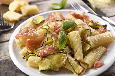 Tasty rigatoni pasta with courgette, prosciutto ham and grana padano cheeseの写真素材