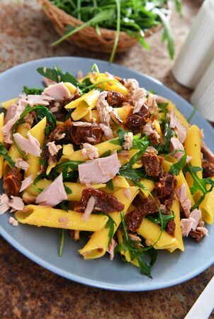 Penne pasta with tuna chunks, rucola and dry tomatoesの写真素材