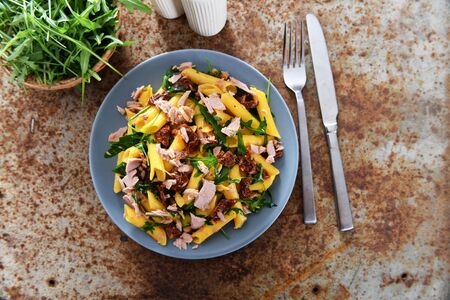 Penne pasta with tuna chunks, rucola and dry tomatoesの写真素材