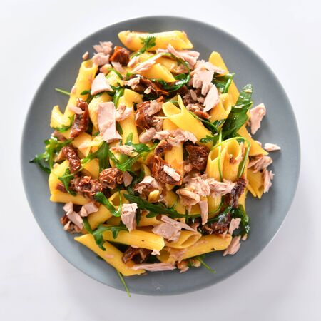 Penne pasta with tuna chunks, rucola and dry tomatoesの写真素材