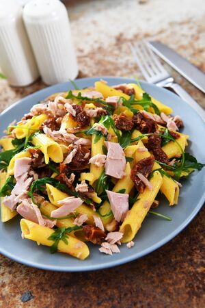Penne pasta with tuna chunks, rucola and dry tomatoesの写真素材