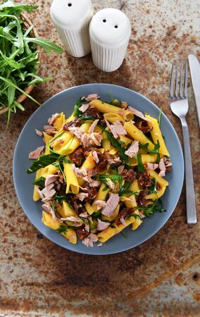 Penne pasta with tuna chunks, rucola and dry tomatoesの写真素材