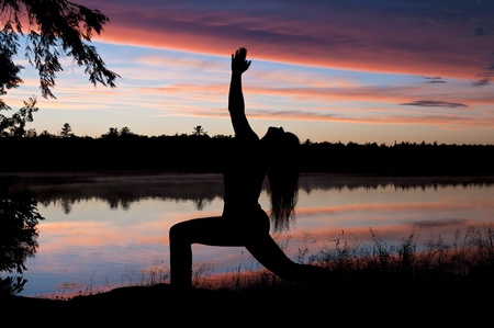 Girl Practicing Yoga by the lake at Sunsetの写真素材