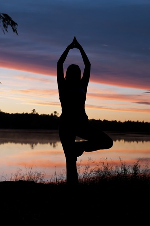 Girl Practicing Yoga by the lake at Sunsetの写真素材