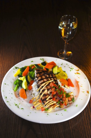 Grilled fish on a white plate with rice and vegetables glass of wine の写真素材