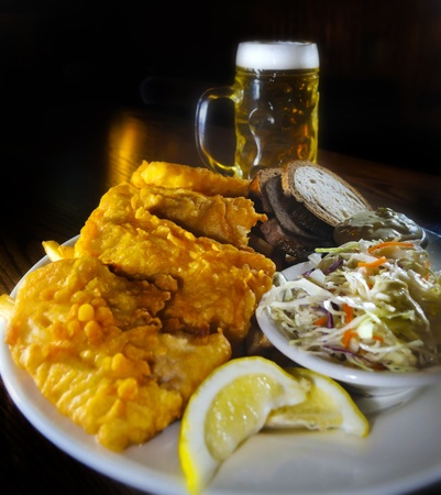 Fried Fish with coleslaw bread and tartar sauce, glass of beer in the backの写真素材