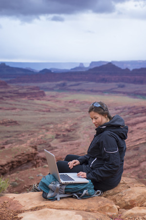 Girl Hiker on top of the mountain with her laptop computerの写真素材