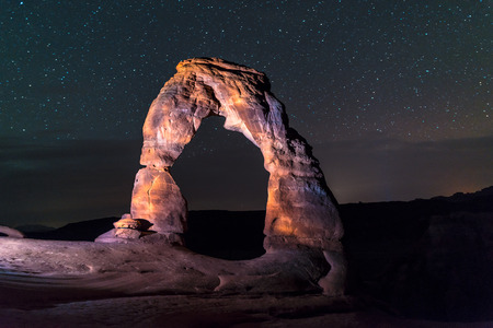 Famous Utah Landmark Delicate arch photographed at night with clead skies and shooting starsの写真素材