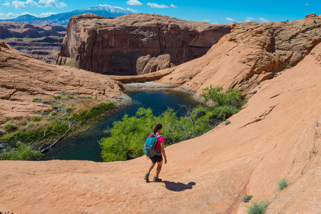 Hiker walking down the slick rock towards small lake  Horizontal Compositionの写真素材