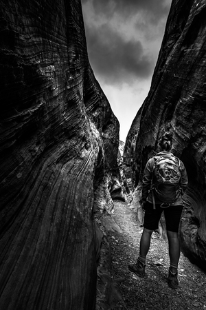 Hiker inside slot canyon Black and White hight contrast vertical composition