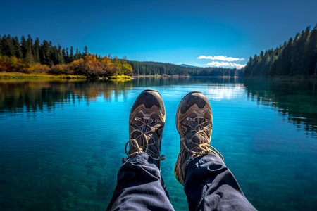 Female Feet Wearing Hiking boots over Clear Lake Oregonの写真素材