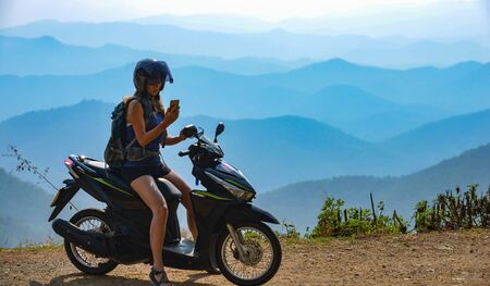 Young Woman on a motorcycle on top of a Samoeng Loop overpass overlooking Mea Sa Valleyの写真素材