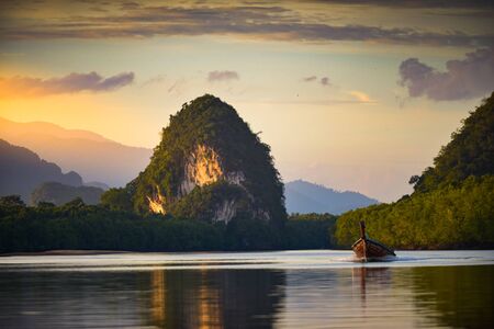 Thai longtail boat in Krabi Thailand Limestone Cliffs and Pak Nam River at Sunset