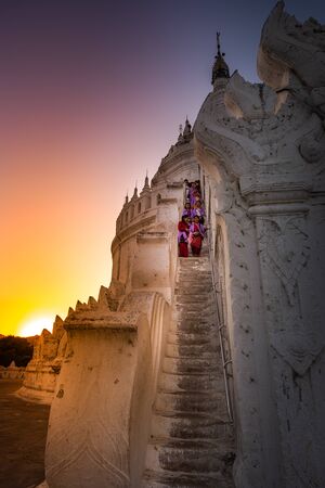 Mingun, Myanmar. January 02, 2019: Unidenified smiling girls  in tradition burmese clothes walking down stairs at beautiful white Hsinbyume Pagoda at sunset in Mingun.のeditorial素材