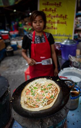Yangon, Myanmar. December 24, 2018: An unidentified Burmese woman preparing traditional Indian Dosa pancake and sells it at local market.のeditorial素材