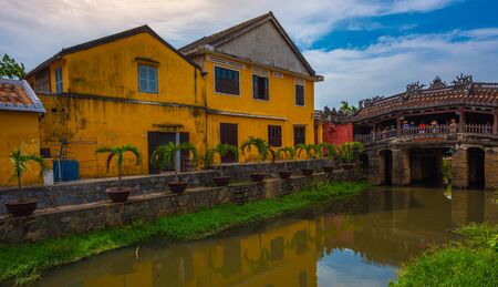 Japanese Bridge and old yellow buildings in ancient town Hoi An, Vietnamの写真素材