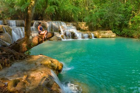 Tat Kuang Si Waterfalls Luang Prabang northern Laos Young Woman posing on a tree trunkの写真素材