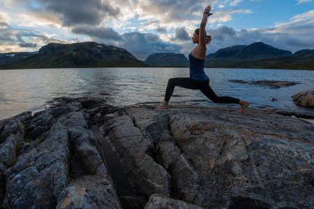 Woman practices yoga on the rocky shore of Stavatn Lakeの写真素材