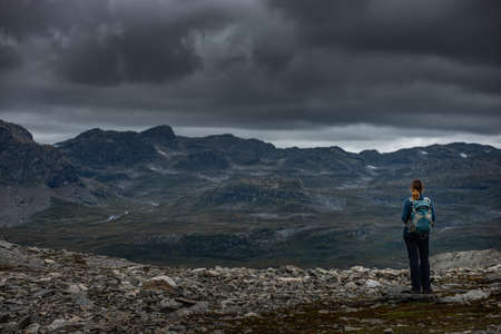 Tourist looking at dramatic sky above Haukelifjell mountainsの写真素材