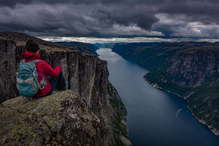 Backpacker sits on top of the Eagle Head Viewpoint near Kjeragboltenの写真素材