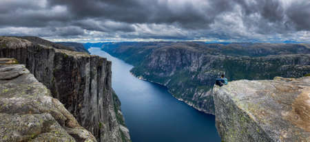 Backpacker sits on top of the Eagle Head Viewpoint near Kjeragboltenの写真素材