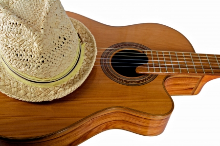 Straw Fedora Hat Rests Atop an Acoustical Guitar against a white backgroundの写真素材