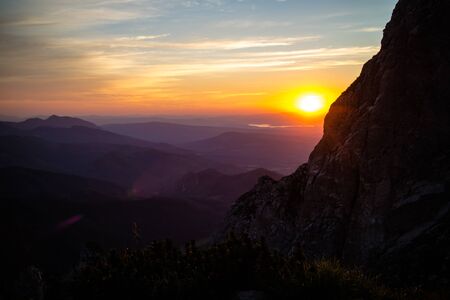 Purple silhouettes of Carpathian rocky mountains and sunset orange-blue sky with cloudsの写真素材