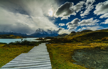 View of a wooden path and mountains in the Torres del Paine National Park on a cloudy day. Autumn in Patagonia, the Chilean sideの写真素材