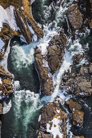 Aerial view of Godafoss waterfall, snowy shore and river. Iceland in early spring.