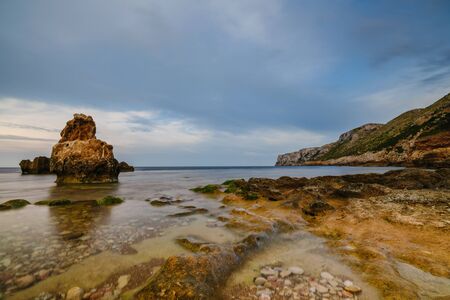 Sunset on the beach among the rocks near the city of Denia. District of Valencia, Spain.の写真素材